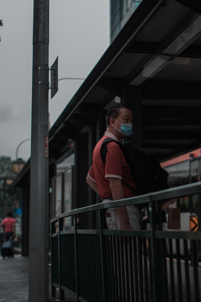 白天站在黑色金属栏杆旁的身穿黑色夹克和橙色夹克的男子